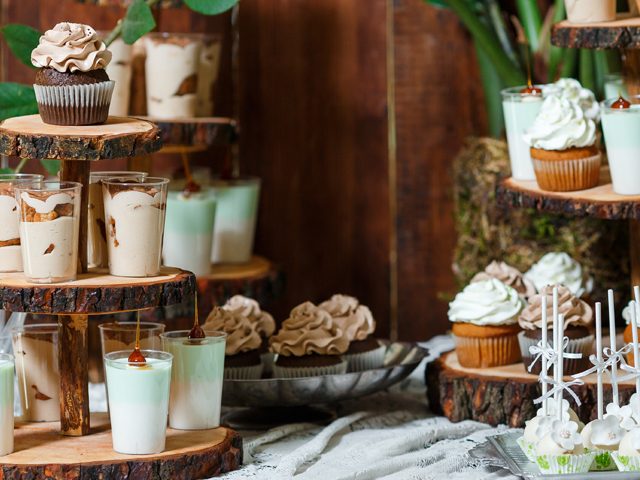 Candy bar on wooden wedding party with a lot of different candies, cupcakes, souffle and cakes. Decorated in brown and green colors, nature and eco theme, indoor